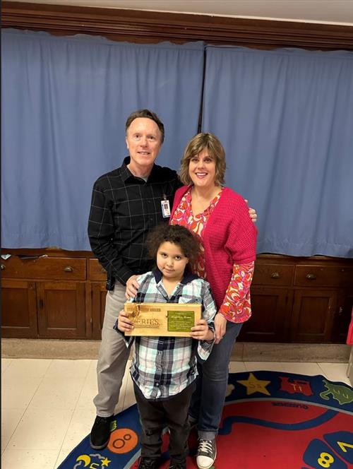 Perry's March Stairclimber, Madelyn Mann, posing with her plaque, Principal Dave Eubank, and a female adult.